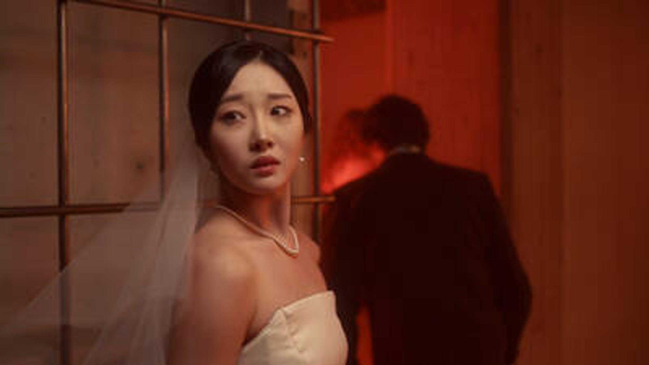 Surullisen näköinen nainen katsoo kameran ohi, kun mies poistuu hänen luotaan