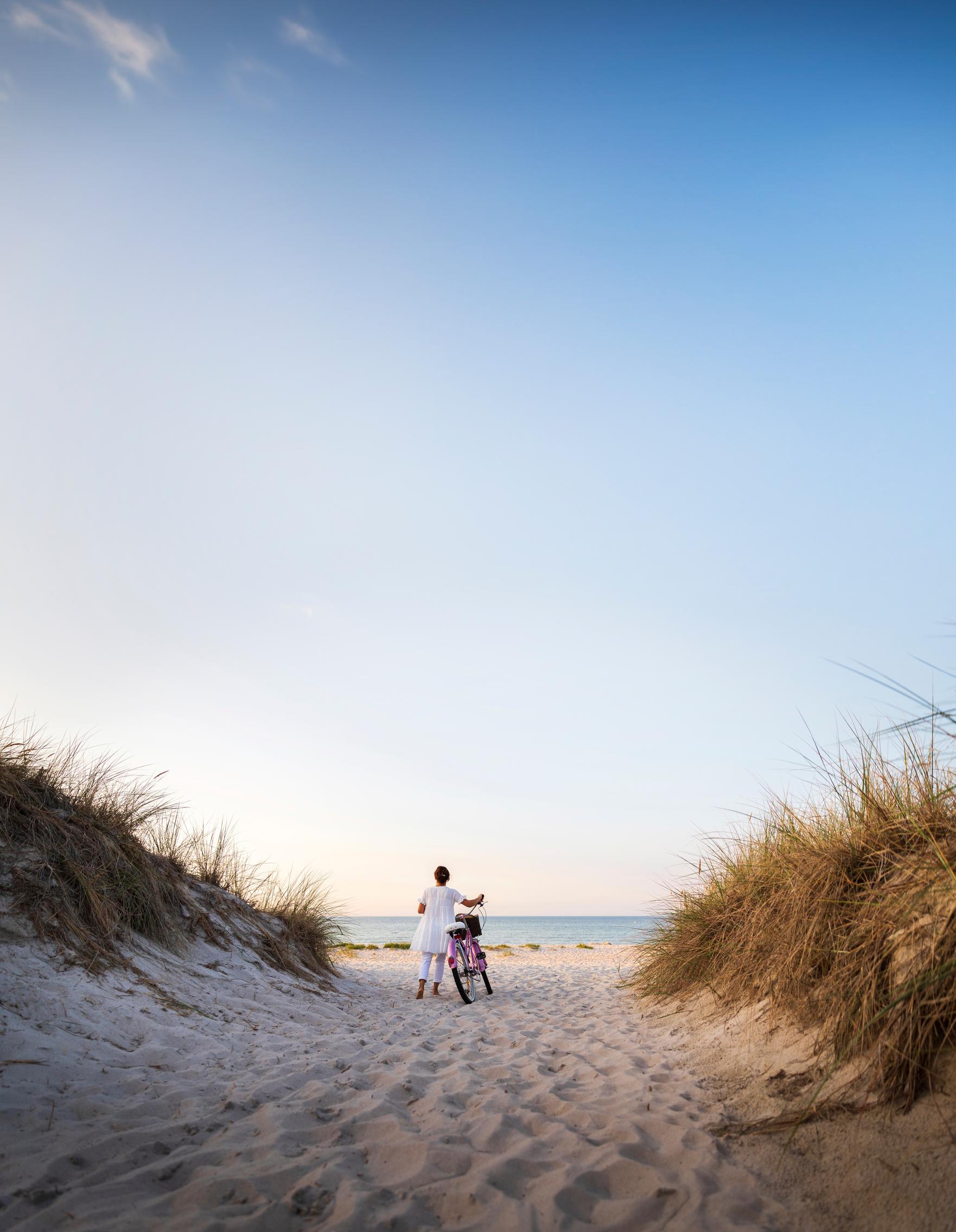 Nainen pyörän kanssa rannalla