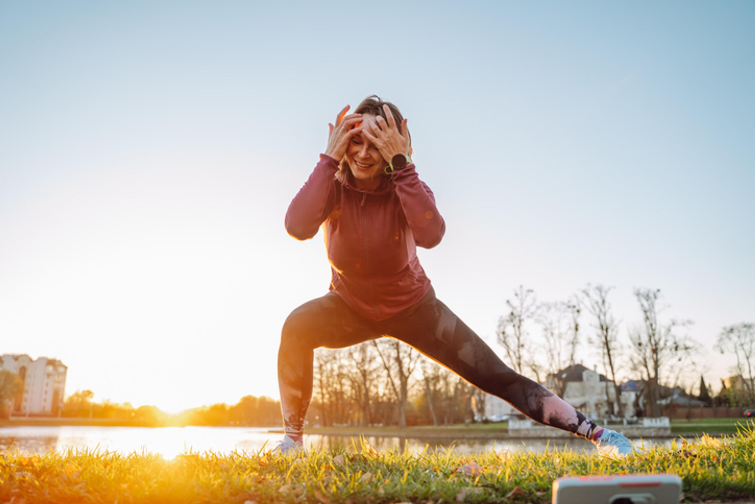 Nainen venyttelee järven rannalla