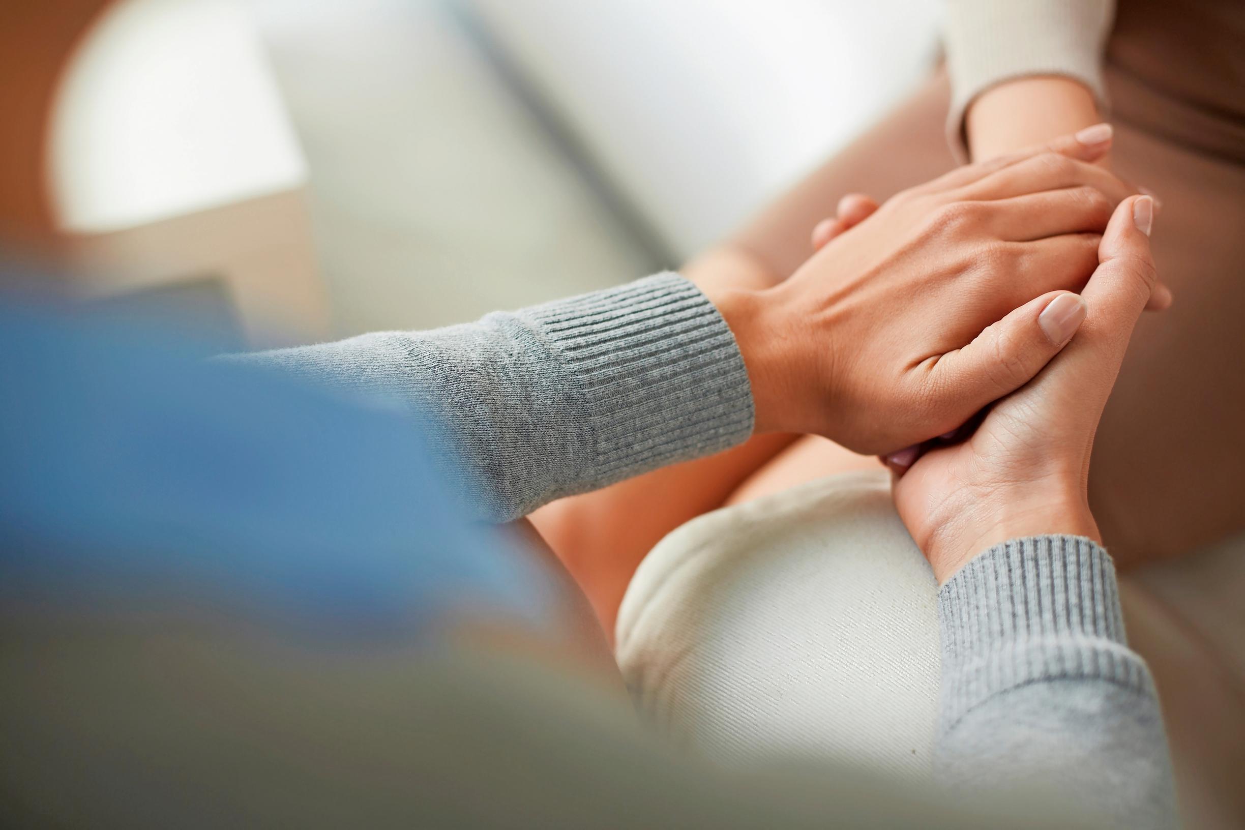 Kaksi ihmistä pitää toistensa käsistä kiinni lähikuvassa