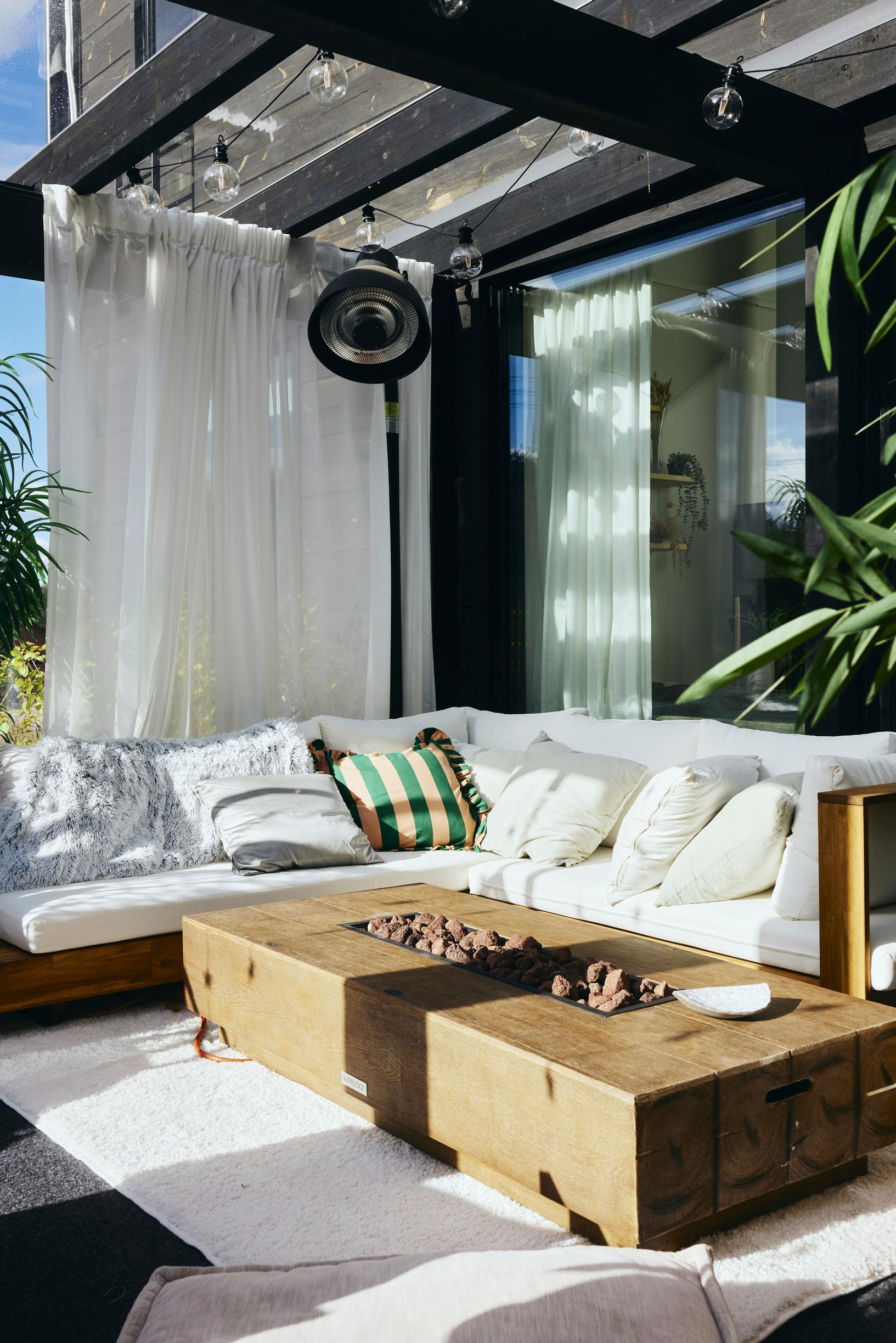 Terassin pöydän tulisija tuo lämpöä suurellekin seurueelle. Sohva on ystävien kokoontumispaikka.