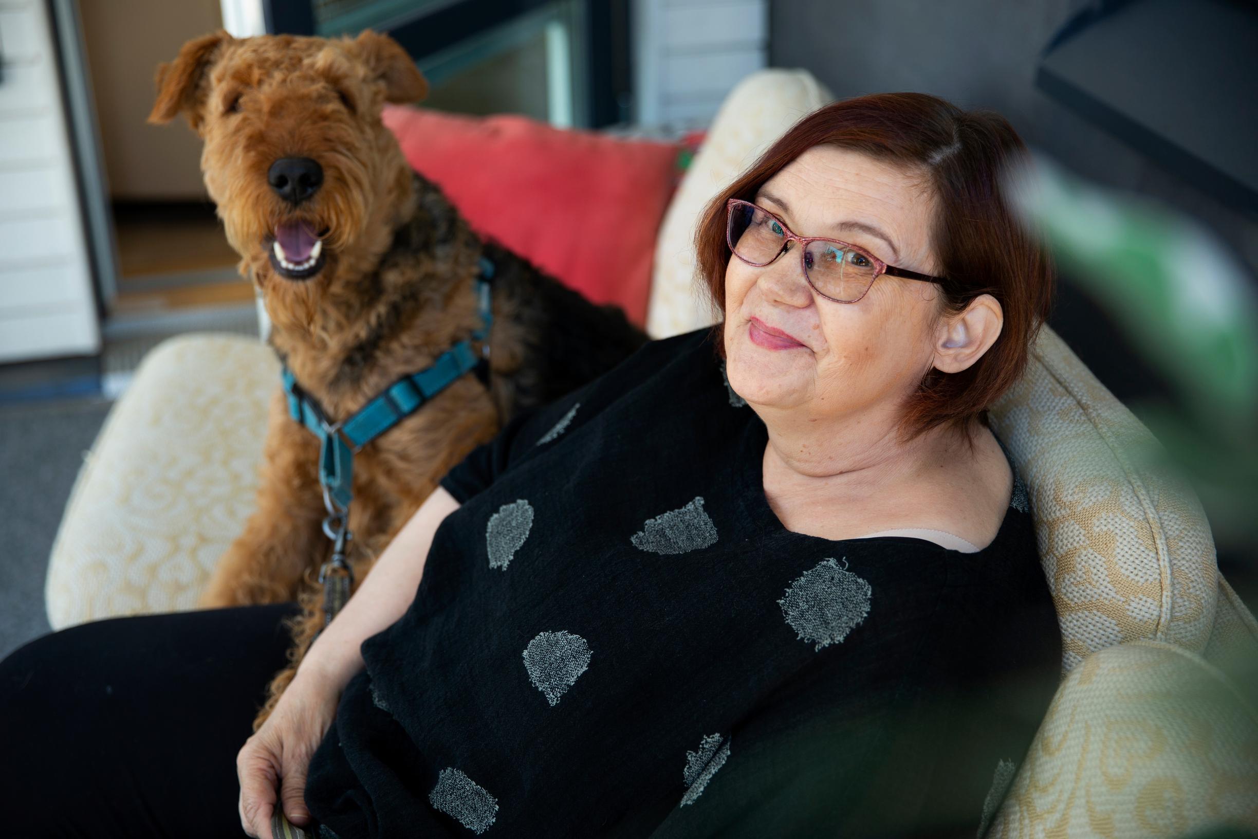 Tarja Miettinen istuu sohvalla koiransa kanssa.