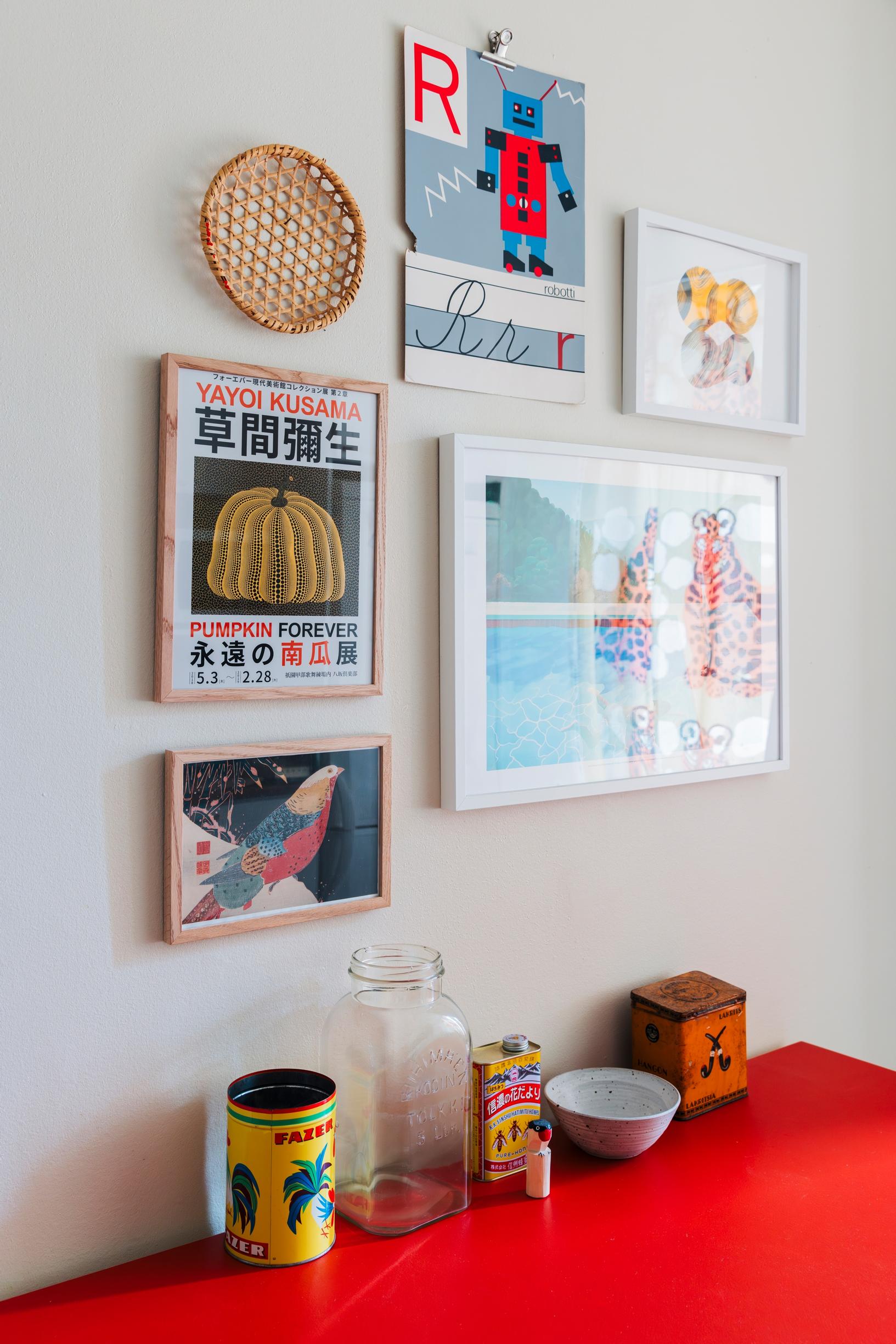 Keittiön ruokapöydän yllä on pirteä galleria julisteita ja piirroksia.