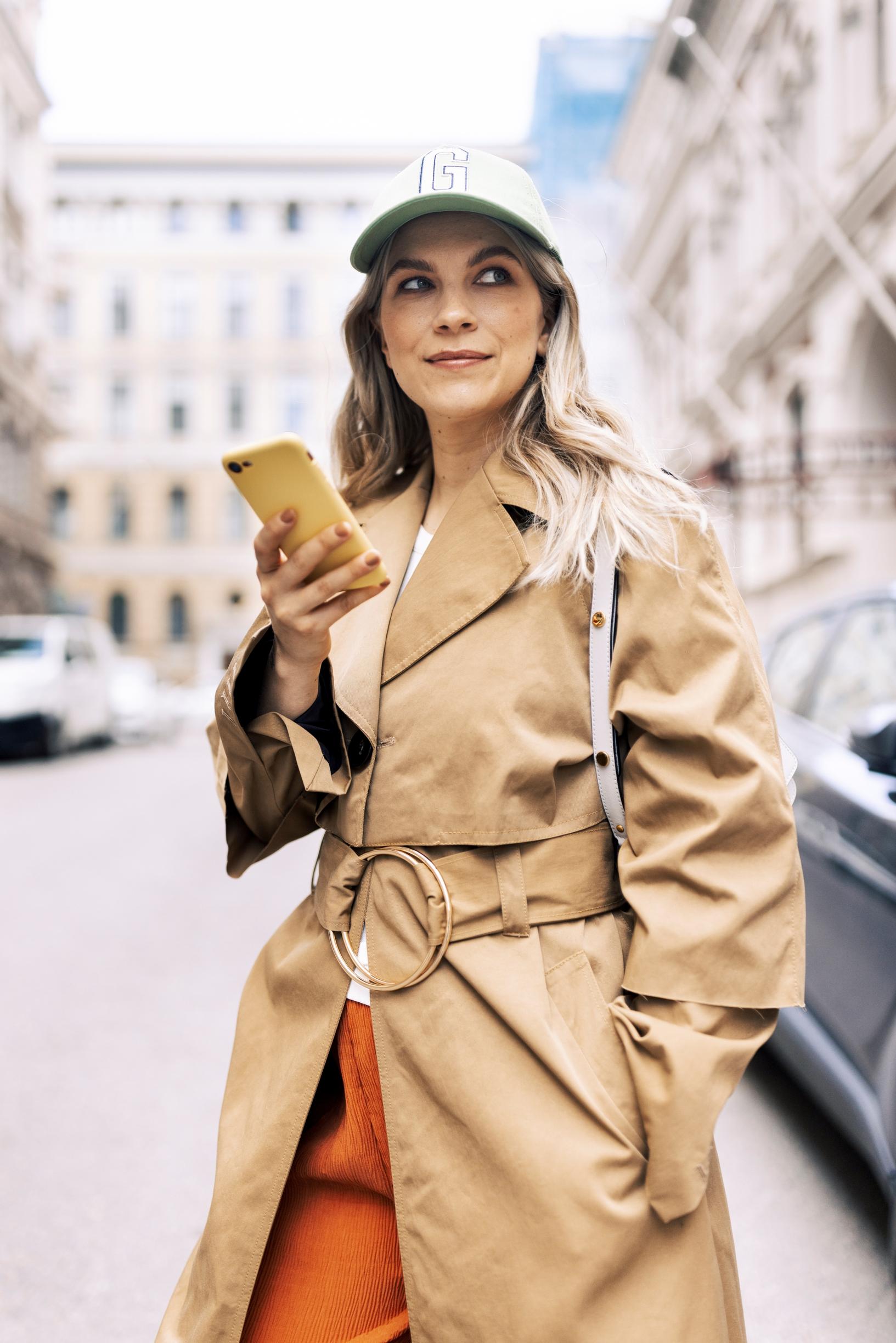 Emmi-Liia Sjöholm kaupungilla yllään beige trenssitakki.