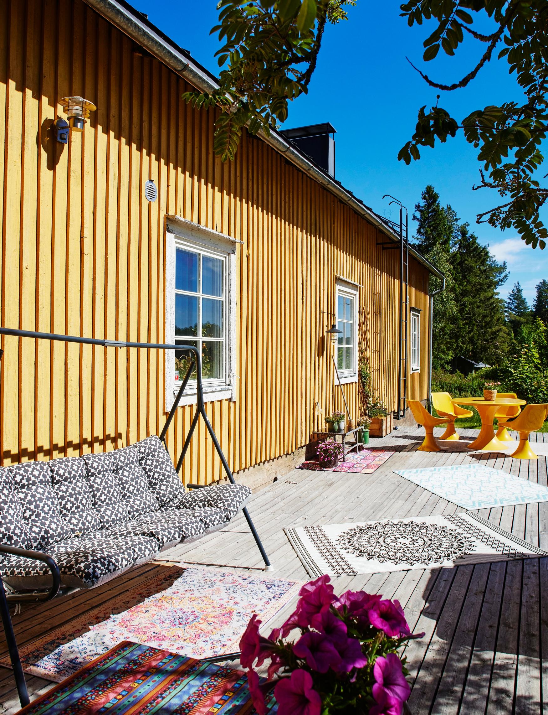 Koko talon levyisellä terassilla nautitaan kesällä auringosta. Keltainen ruokailuryhmä on puoliso Panu Varstalan kierrätyslöytö.