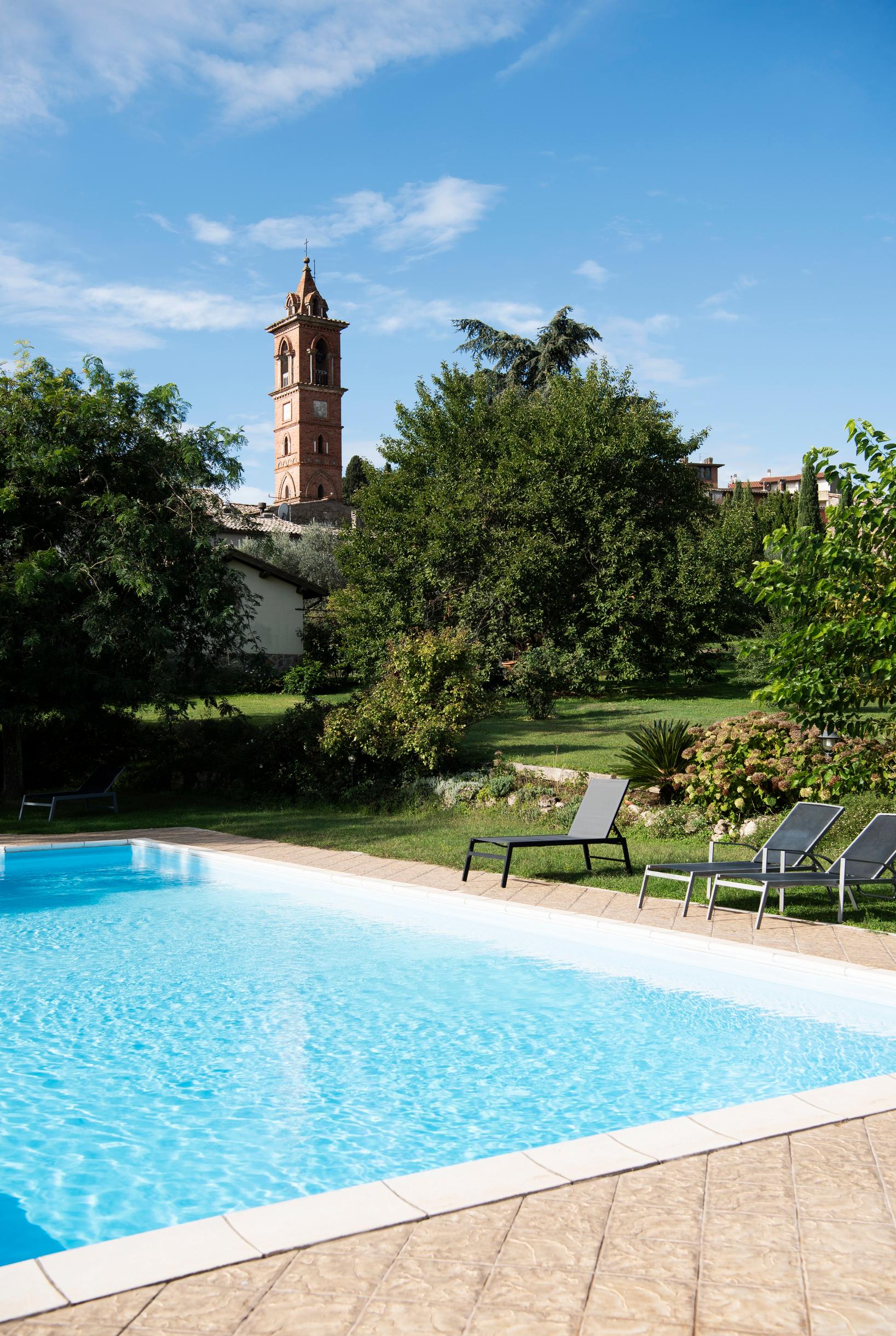 [Image] Viiden talon yhteisessä käytössä olevalta uima-altaalta näkyy Castel Cellesin kirkon, Chiesa di San Girolamon, punatiilestä rakennettu kellotorni.