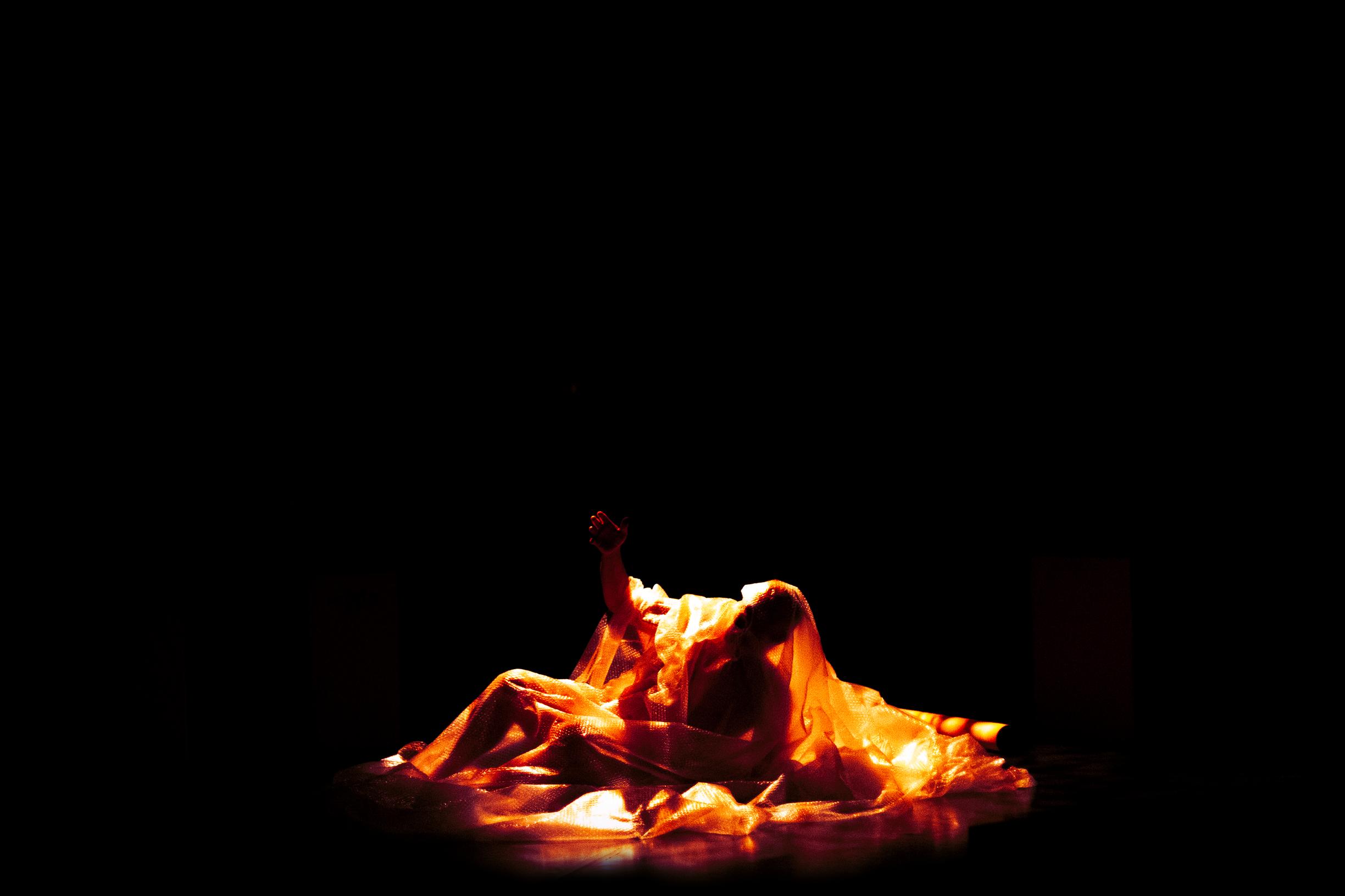 Mies harson alla valaistuna pimeässä tilassa