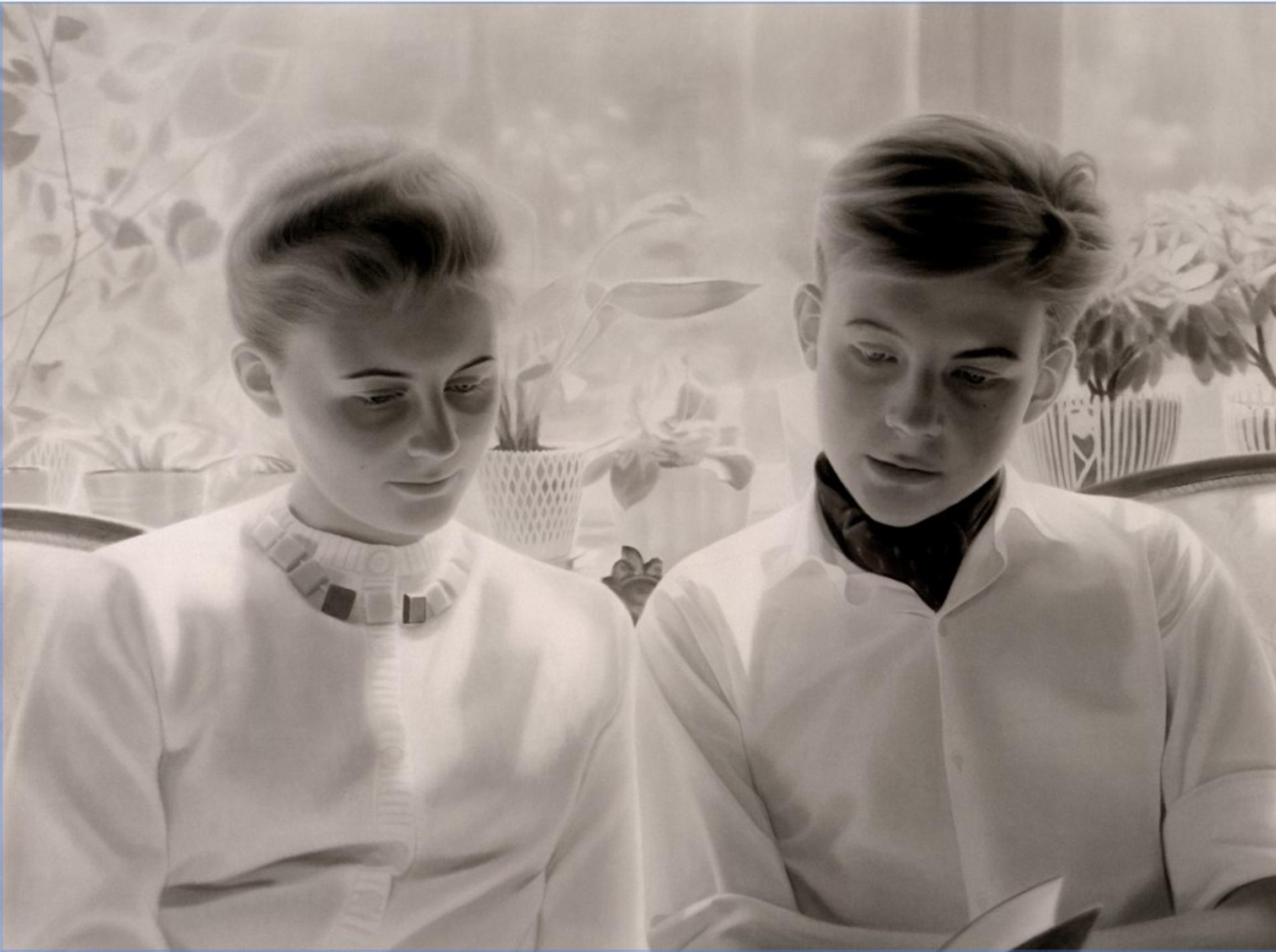 Kaksi ihmistä ikkunan ääressä vierekkäin istumassa, katse kirjassa