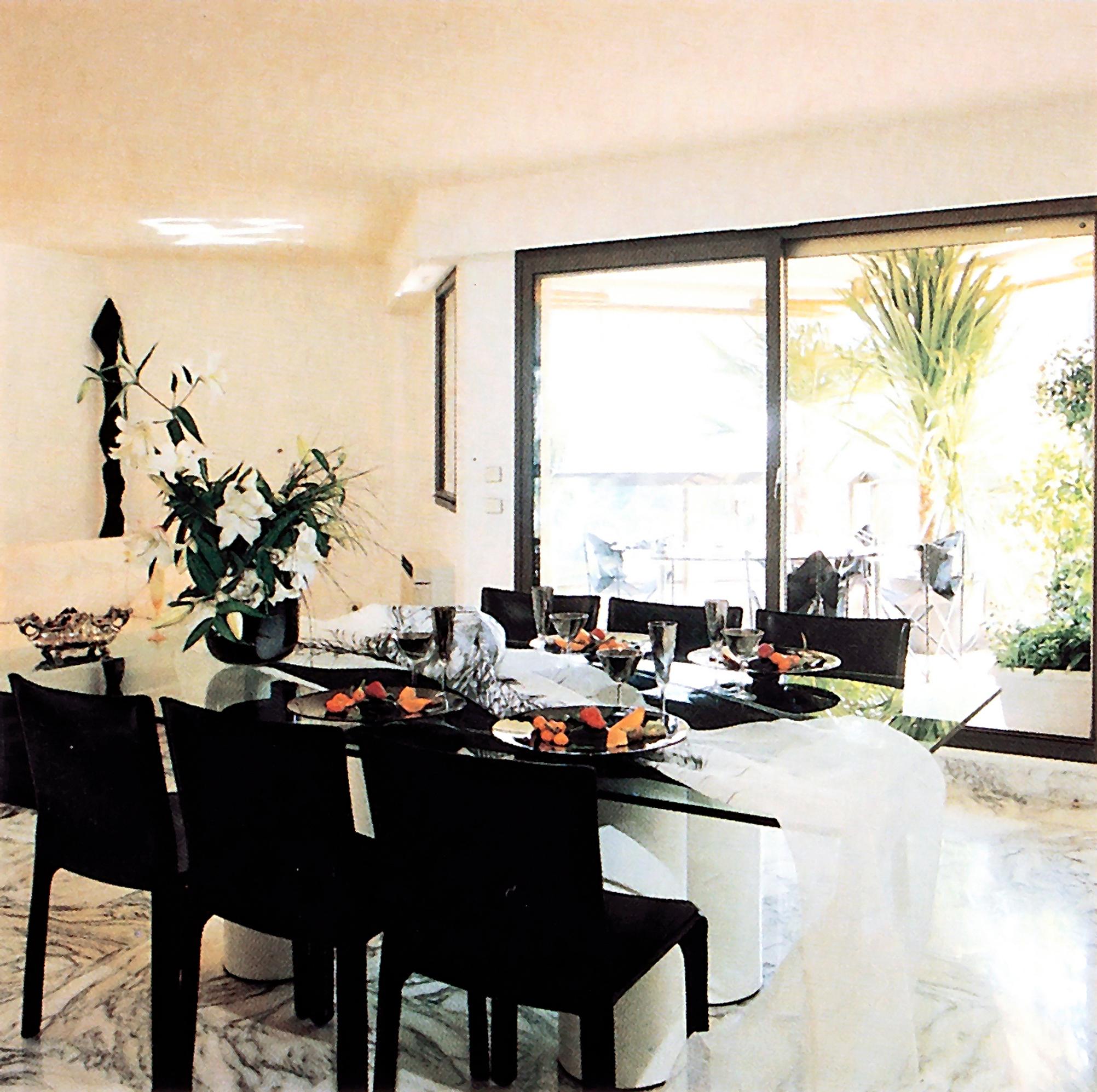 Lasipöytä ja mustat nahkatuolit muodostivat vahvan kontrastin. Liukuovien takana avautui toinen asunnon suurista parvekkeista.