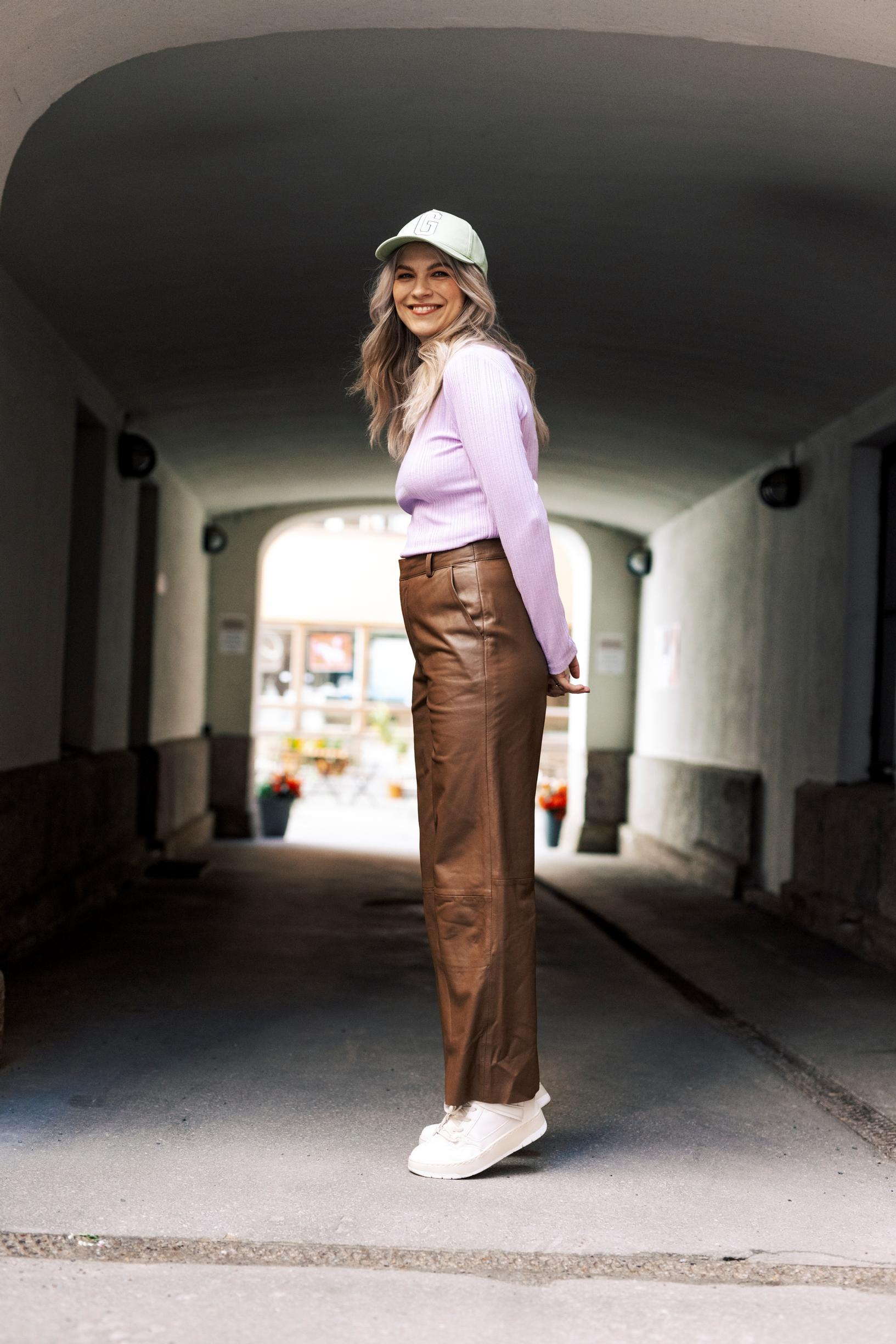 Emmi-Liia Sjöholmin yllä ovat nahkahousut, paita ja lippis.