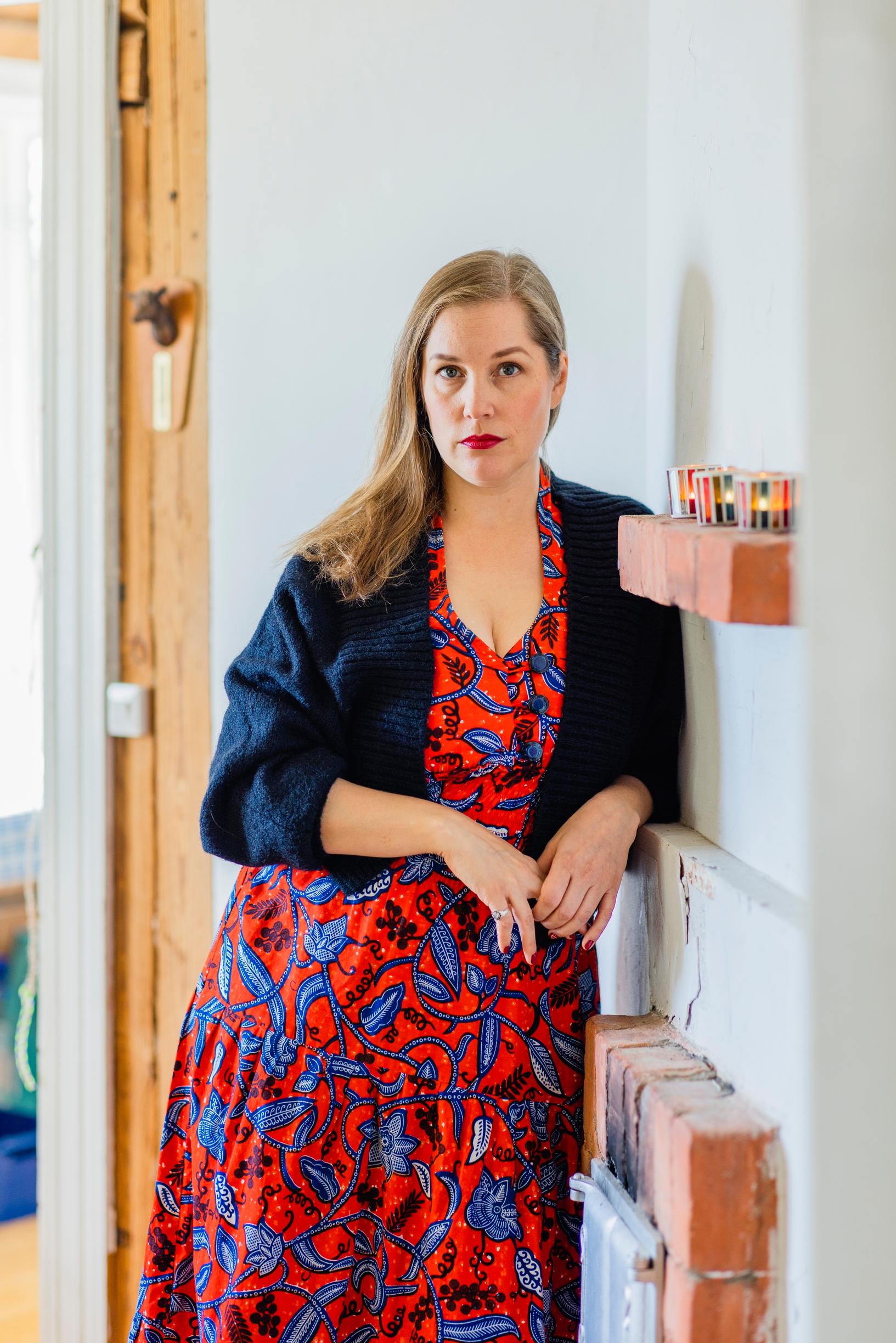 Oona Kapari nojaa seinään ja katsoo kameraan.