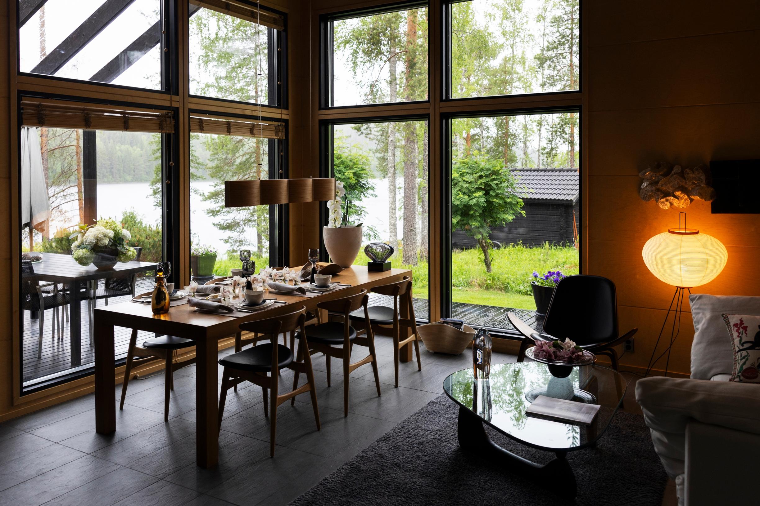 Järvimaisema liittyy osaksi kotia ruokailutilassa. Ateriat nautitaan Zazasta ostetun ison tammipöydän ääressä. Tuolit ovat Hans J. Wegnerin klassikot. Orkideat säilyvät viileässä monta kuukautta. Pöydällä Ritva-Liisan lasityö Kalassa.