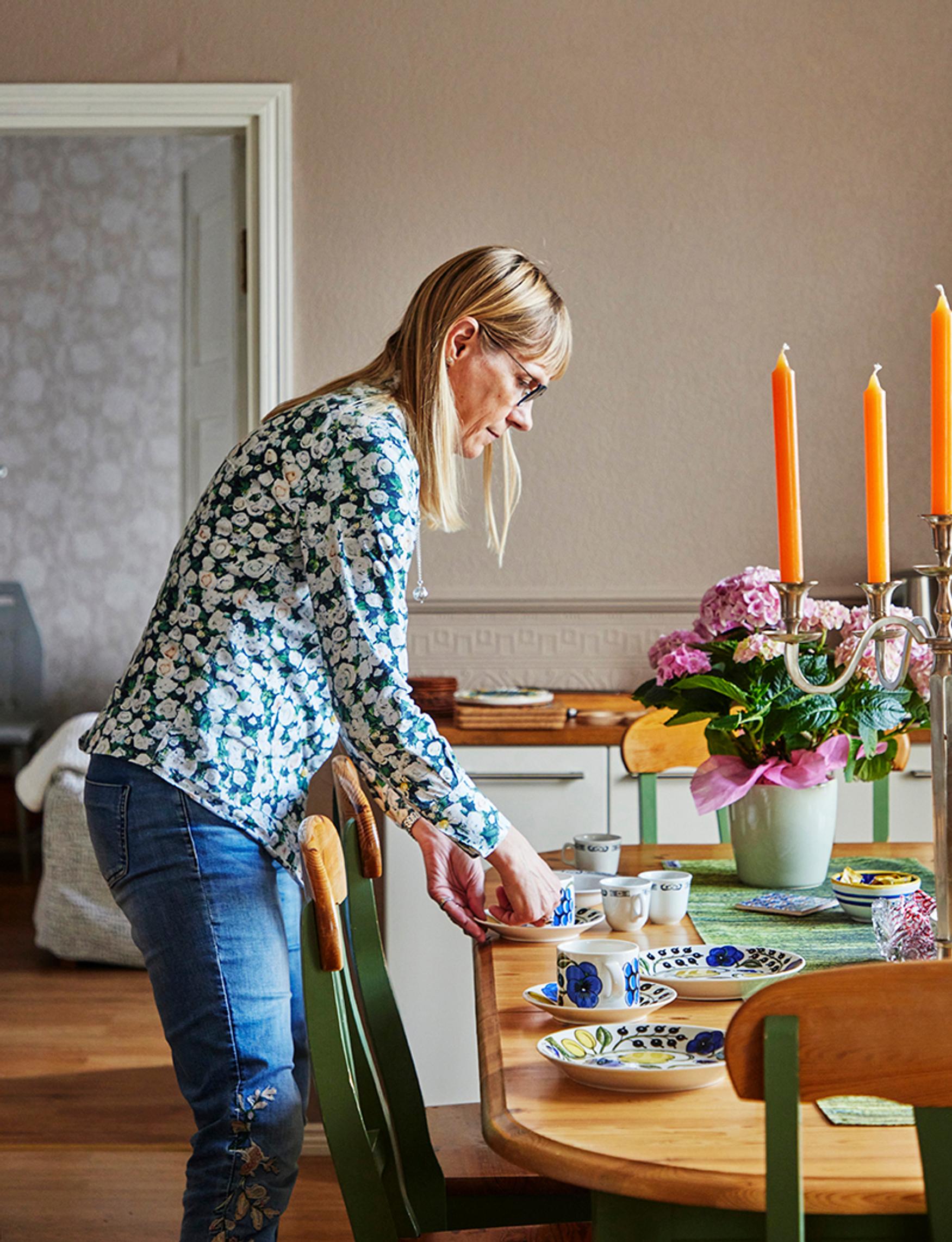 Ruokailutila on keittiön vieressä olohuoneen jatkeena. ”Järjestely oli kuin meille tehty”, Kirsi ja Jari sanovat. Kirsin edessä olevat pienet, vaaleat kahvikupit ovat peräisin Titanicin sisaralukselta.