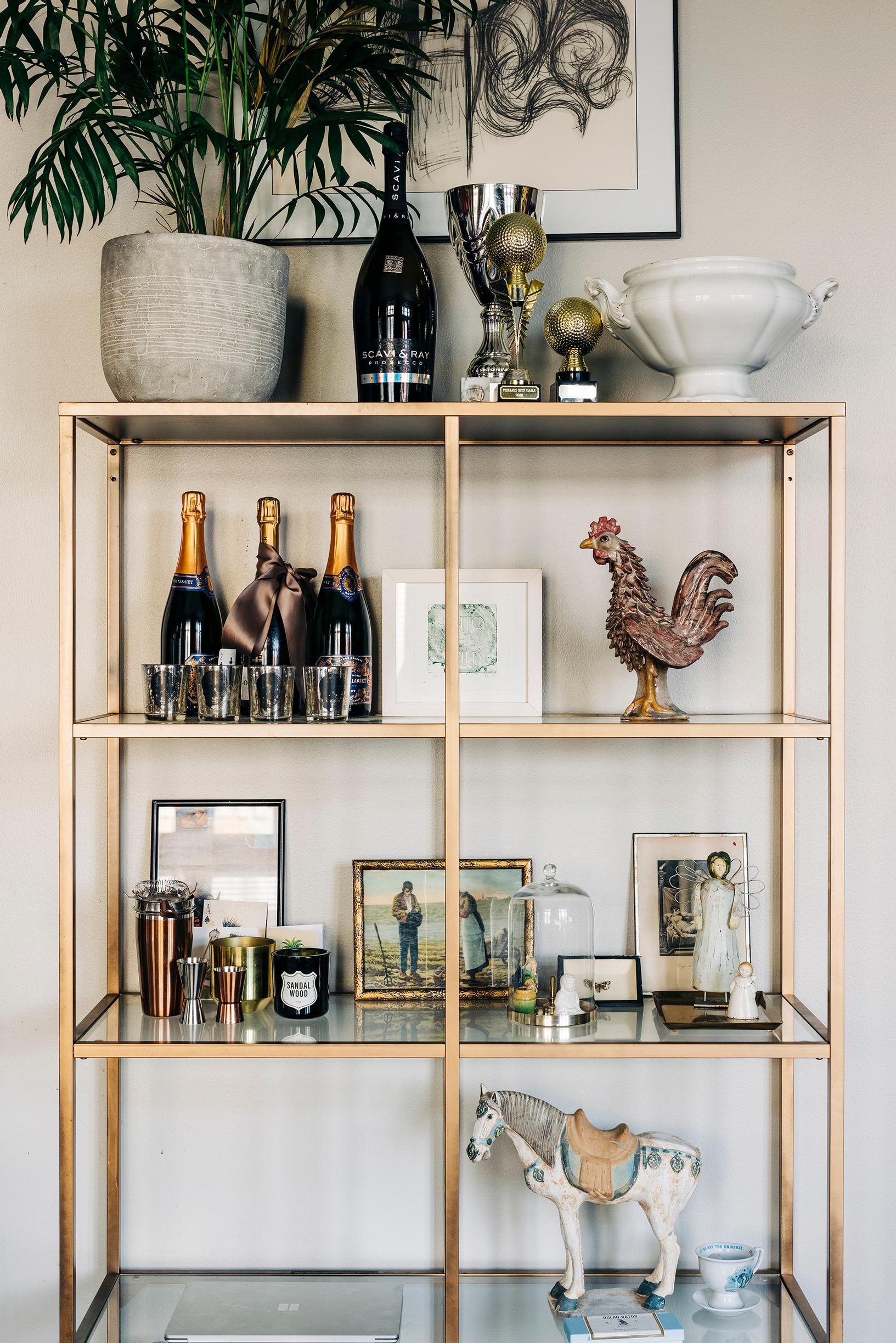 Golfia harrastavan puolison palkintopokaalit ovat esillä sirossa metallihyllyssä Annan lempiviinien kanssa. ”Tämä installaatio ei täytä sisustusoppaan kriteerejä, mutta se ei meitä haittaa”, Anna tuumaa.