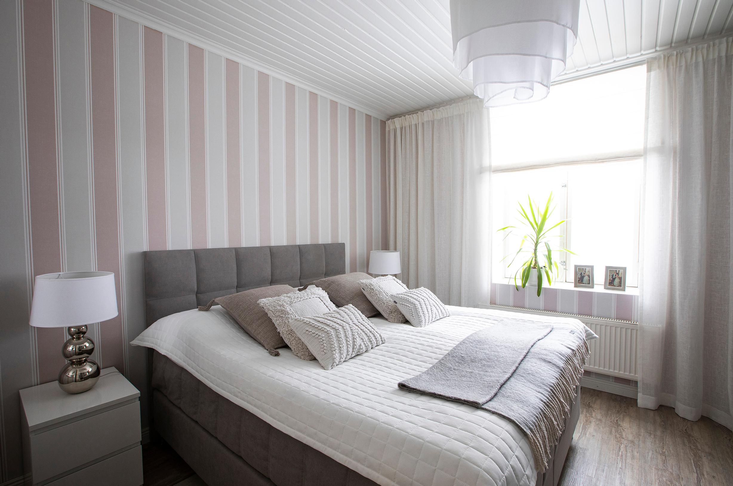 Isäntäparin makuuhuoneessa tärkeää on harmonia. Kotimaisen Doctor Designin Vuolle-riippuvalaisimen muoto on ajaton. Sänky ja tyynyt ovat Askosta, yöpöydän lamppuina ovat Pentikin Rondo- valaisimet.