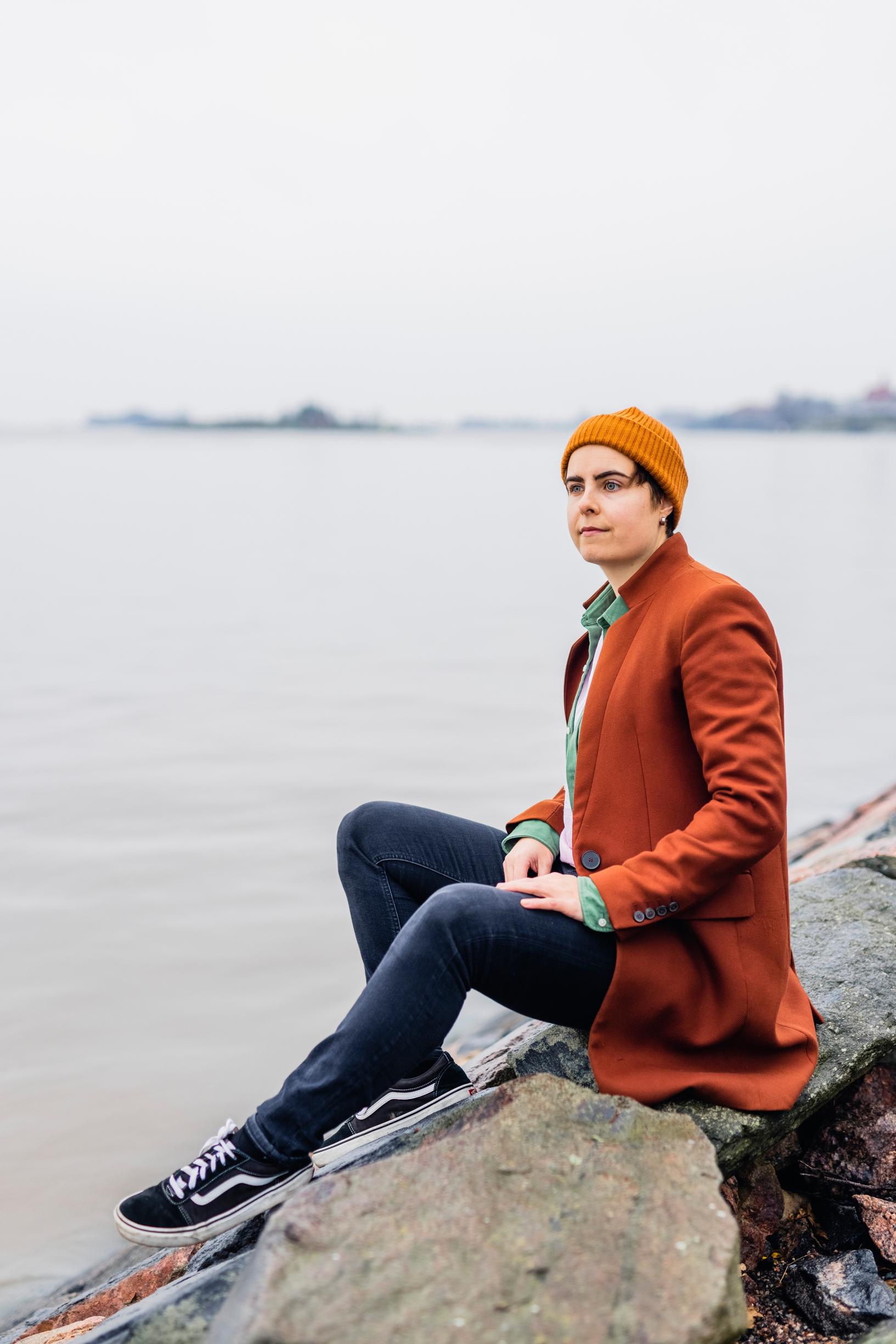 Kuvassa Aino istuu kalliolla