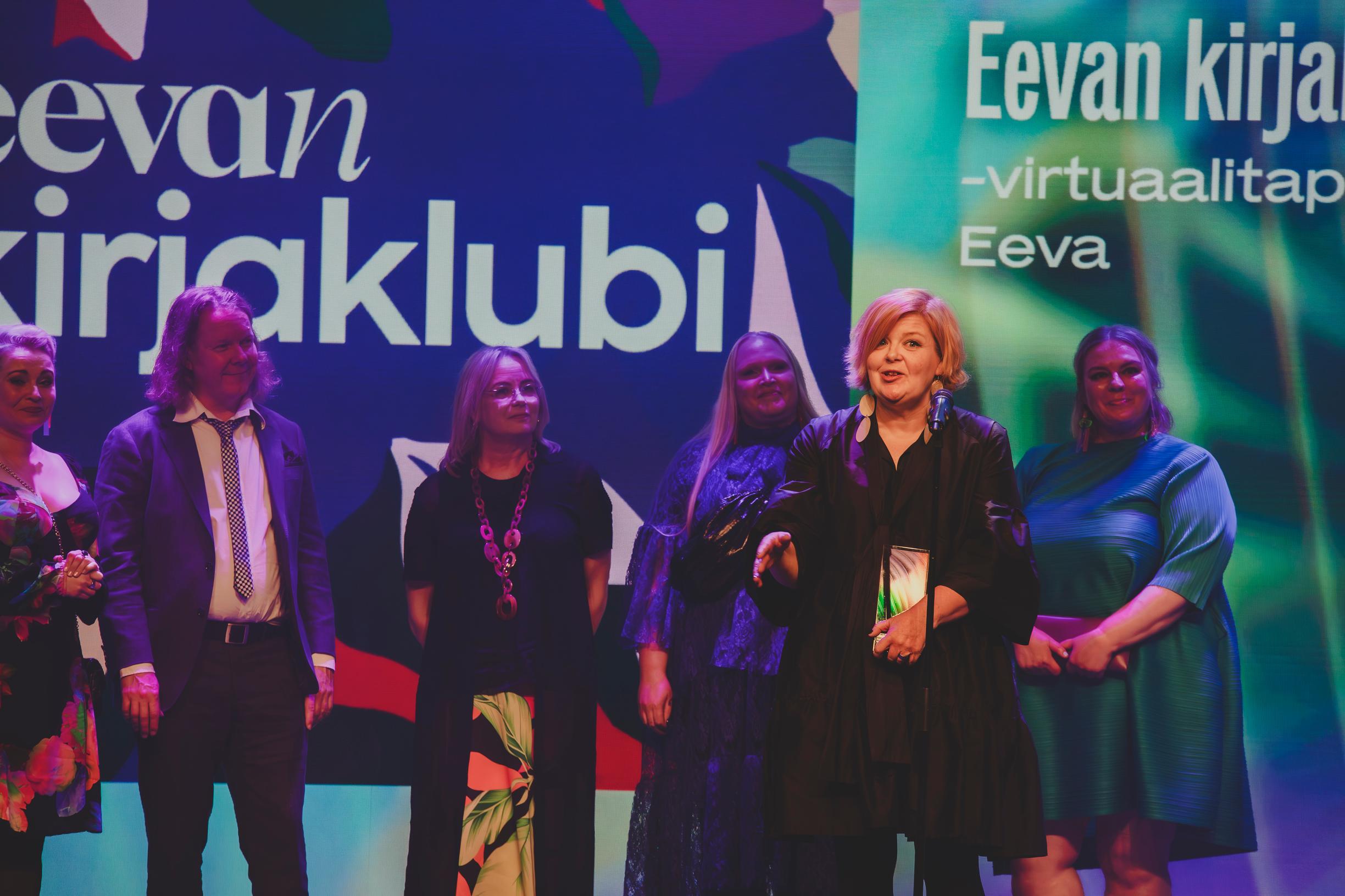Päätoimittaja Mari Paalosalo-Jussinmäki kiittää Eevan kirjaklubin saamasta palkinnosta. Tekijöistä kuvaan mahtuivat myös Katri Koskinen (vas.), Sami Kuusela, Outi Rastas, Reetta Röynä ja Annaleena Jalava.