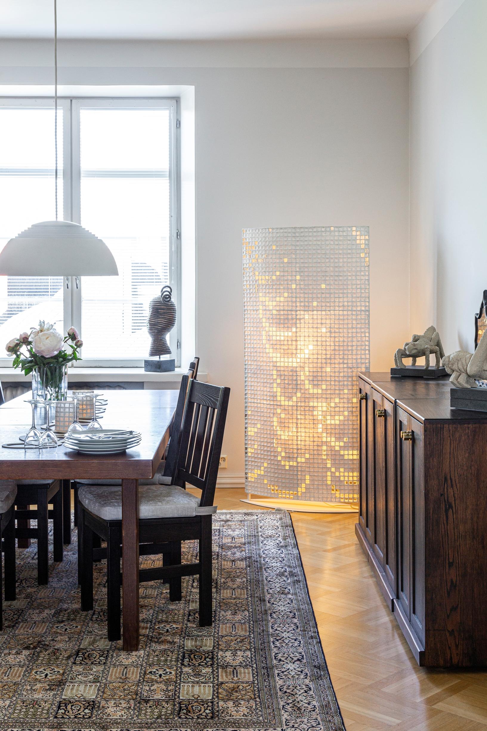 Ruokailutilan valaisin on Arne Jacobsenin Royal. Ikkunalaudalla on Irinan pronssiveistos One Curl, ötökät tammilipastolla ovat saviveistoksia. Ison pellavapaperityön kuvio on isoäidin ristipistokirjasta.