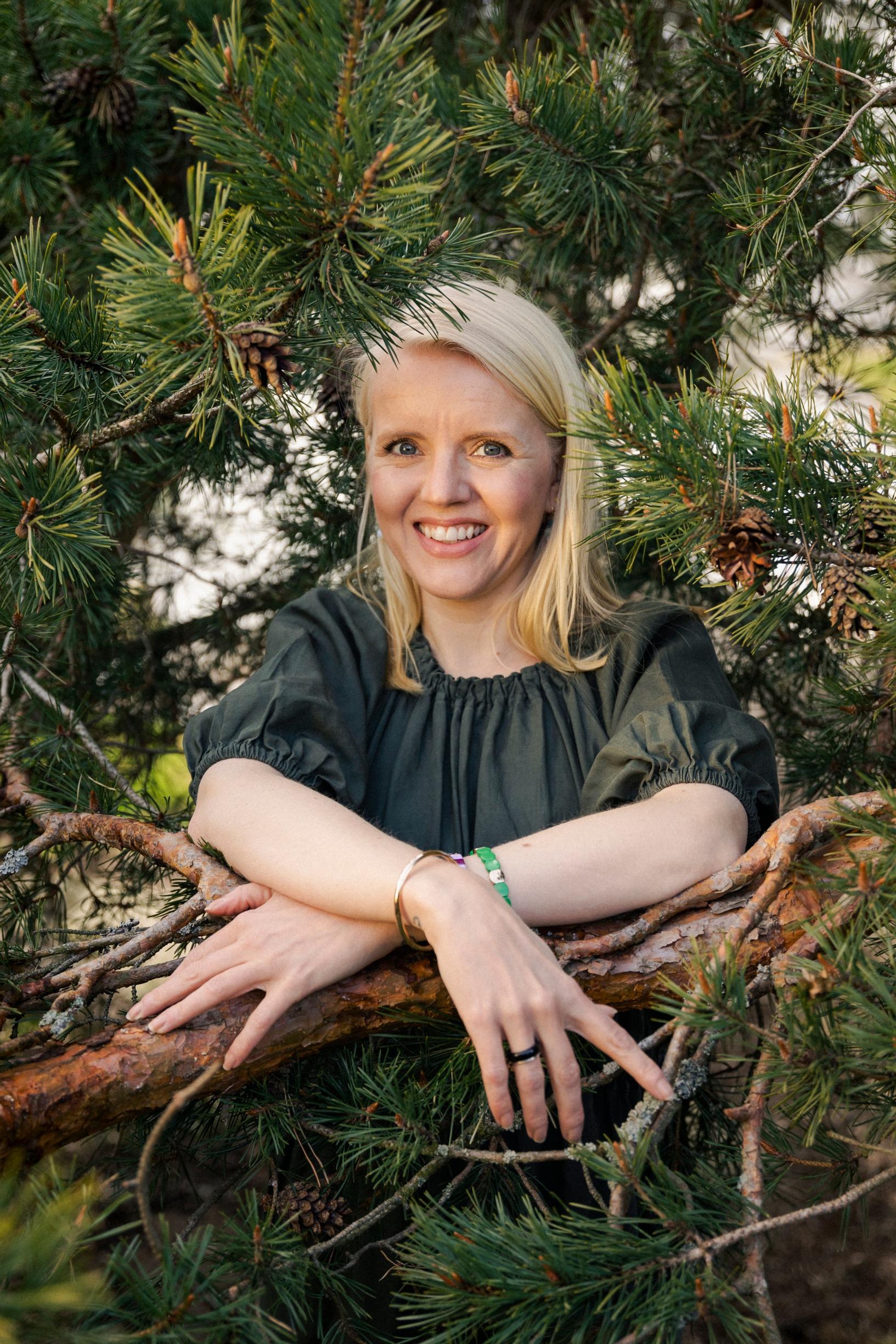 Heli Thorén seisoo havupuun keskellä.